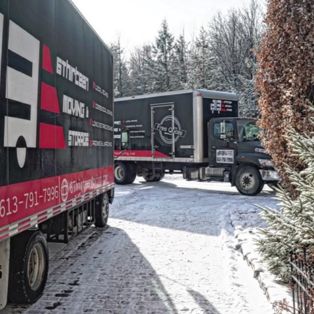 Two branded 6Thirteen Moving & Storage trucks parked beside a snowy driveway